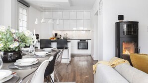 Une cuisine moderne avec des meubles blancs, un îlot central et un poêle à bois noir.