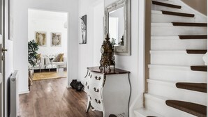 Un escalier avec des marches blanches et des rampes d’appui sombres, menant à un palier où se trouvent une console blanche et un miroir.