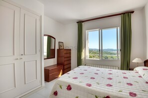 A bedroom with a bed, a dresser, a mirror, a window with curtains, and a view of the landscape. - Wonderfull Sea View  (Calonge)
