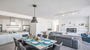 A modern kitchen with a dining area, a living room with a sofa and TV, and a small coffee table. - 5 & 6 OP Villas Fig Tree Bay Protaras Bedrooms 8, Bathrooms 6, Sleeps 20 (Protaras)