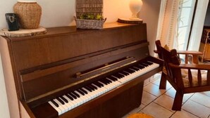 A piano in a room with a lamp, a wicker basket, and a small plant on the piano. - Nomad Room (Corcoué-sur-Logne)