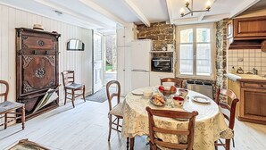 Un coin repas avec une table ronde, des chaises et un lustre. Il y a également une cuisine équipée d’un réfrigérateur, d’un four et de placards.