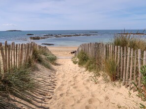 A sandy beach path leading to the sea, flanked by wooden fences and vegetation. - Maison de Saint-Cado by Interhome (Belz)