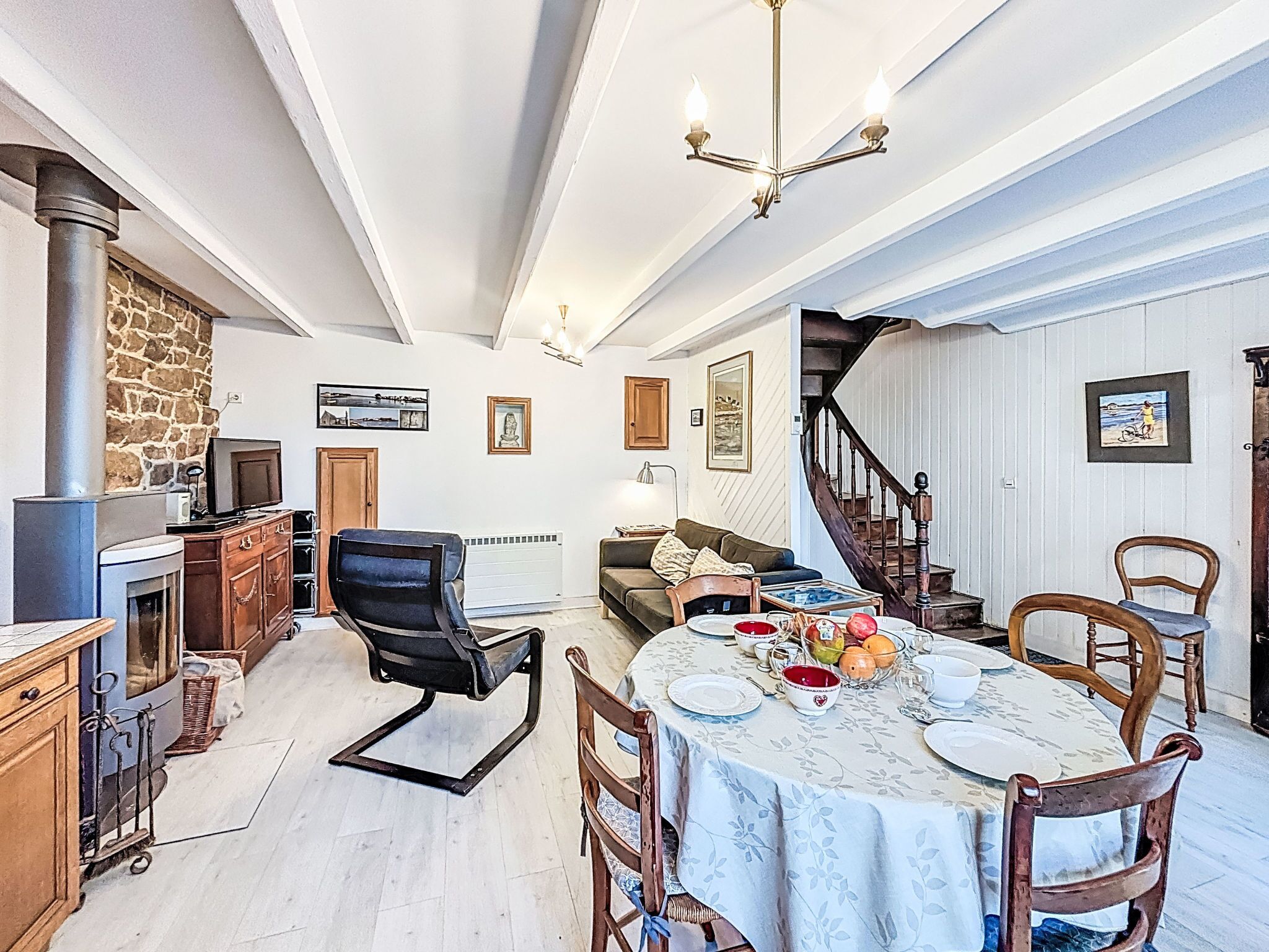 A spacious living room with a fireplace, a dining area with a table set for four, and a staircase leading to another level.