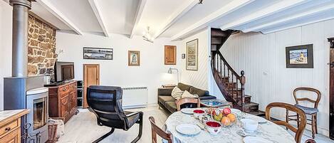 A spacious living room with a fireplace, a dining area with a table set for four, and a staircase leading to another level.