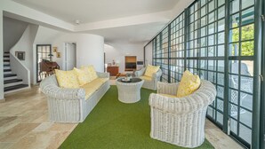 A spacious living area with wicker furniture, a green rug, and large windows. - Villa Lala, a chic getaway with pool and sea view (Case-Pilote)