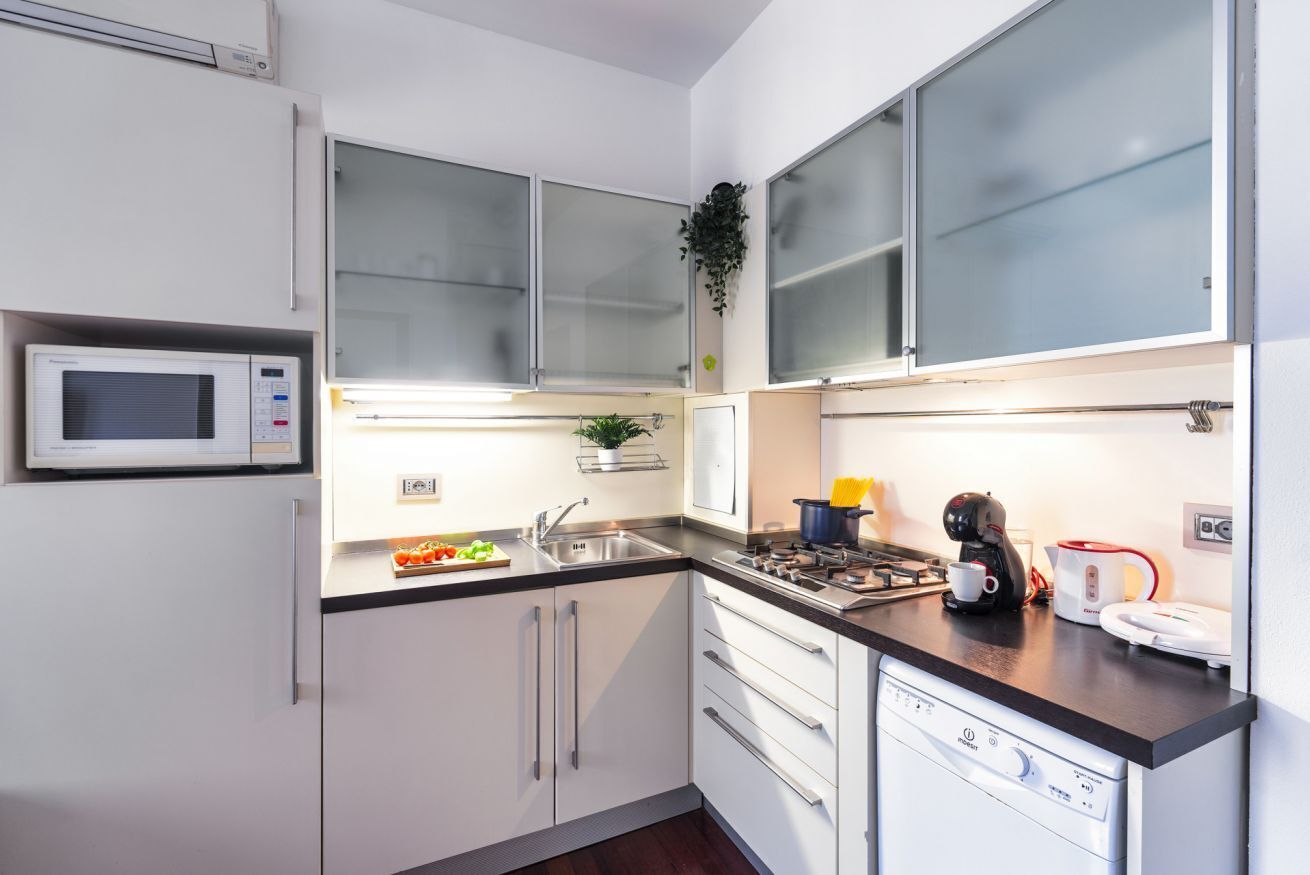 A modern kitchen with white cabinets, a microwave, a sink, a stove, and a dishwasher.