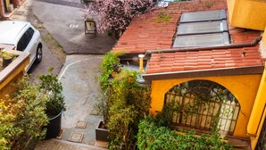 A courtyard with a red-tiled roof, a yellow wall, and a black metal gate. - Cadorna's Nest - Cozy and Central (Milano)