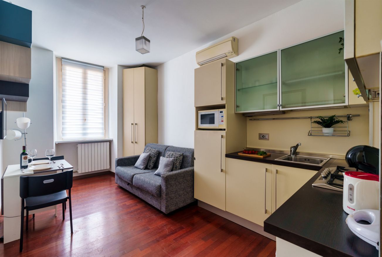 Una cucina compatta con forno a microonde, lavello e un piccolo angolo ristoro con tavolo e sedia.