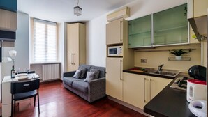 A compact kitchen with a microwave, sink, and a small dining area with a table and chair. - Cadorna's Nest - Cozy and Central (Milano)