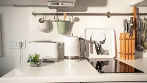 Een keuken met een broodrooster, waterkoker en een wandrek met pannen en keukengerei.