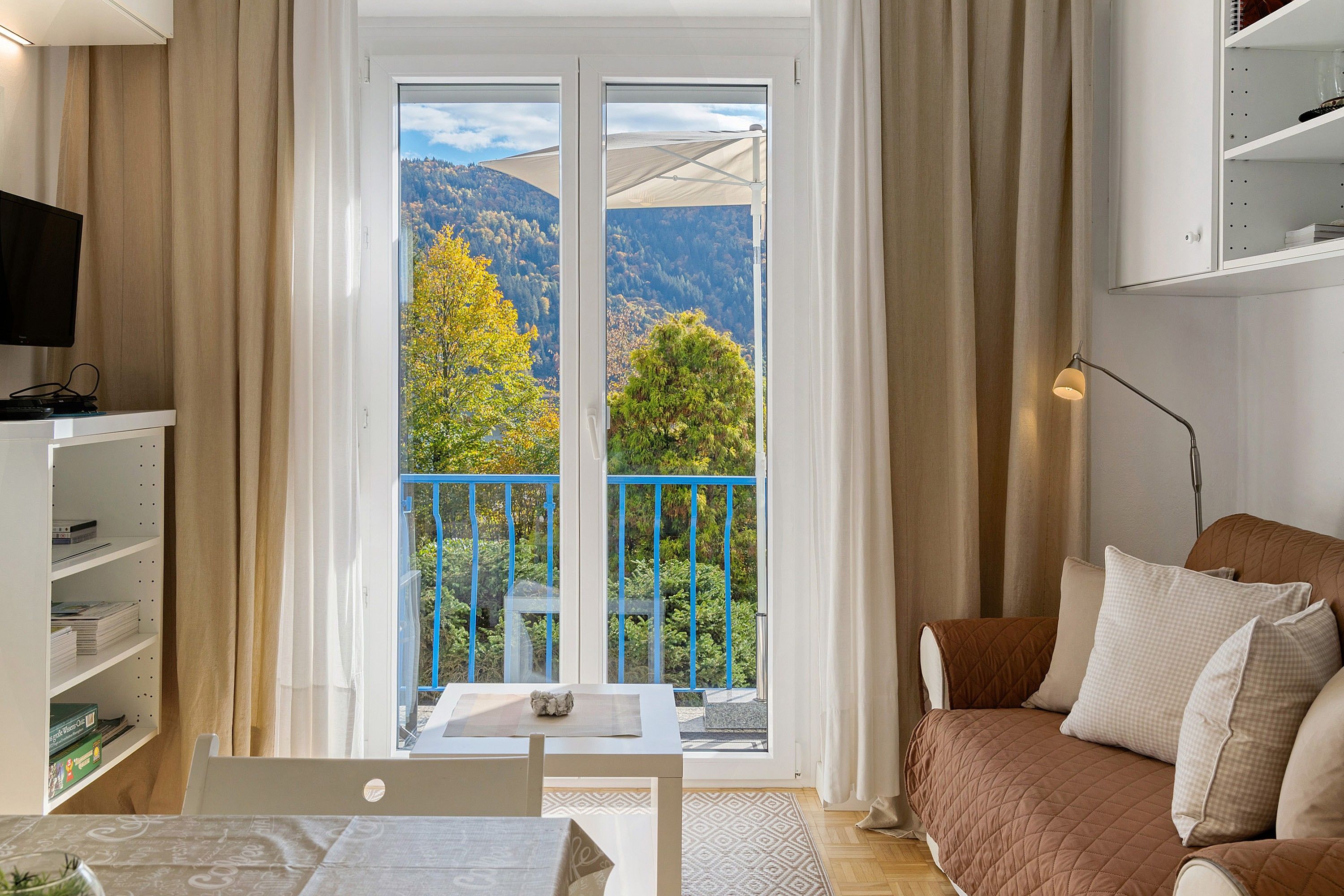 A modern living room with a balcony, a television, and a bookshelf.