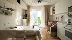 Een moderne keuken met witte kasten, een eethoek met tafel en stoelen, en een balkon met uitzicht.