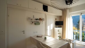 Een moderne kamer met een eettafel, een aan de muur bevestigde televisie en een balkon met uitzicht.
