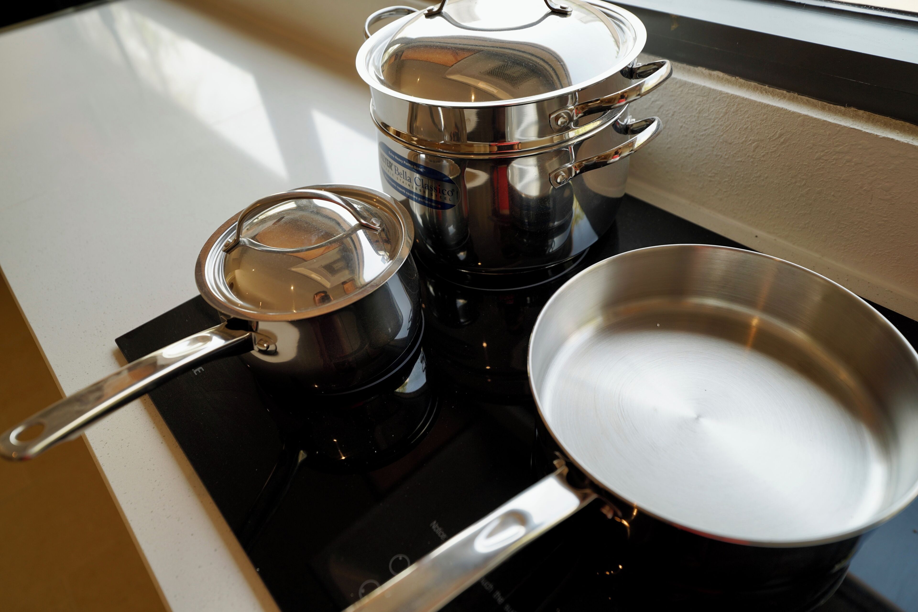 A kitchen with a stove, pots, and a pan.