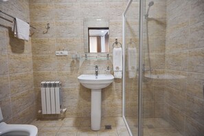 A bathroom with a pedestal sink, a glass shower enclosure, and a toilet. - Art Grand  (Tashkent)