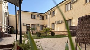 Un pati amb un edifici, escales, plantes en testos i mobles d'exterior.