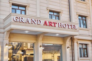Fachada del Grand Art Hotel, con un estilo arquitectónico clásico, que presenta grandes ventanales y una entrada destacada.