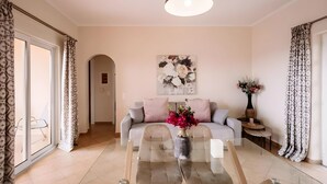 Una sala de estar moderna con un sofá, una mesa de centro de vidrio y un jarrón de flores.