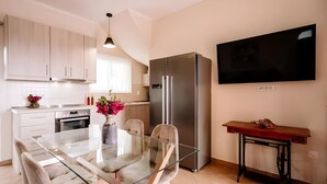 Una cocina moderna con una mesa de comedor de vidrio, un refrigerador de acero inoxidable y un televisor de pantalla plana montado en la pared.