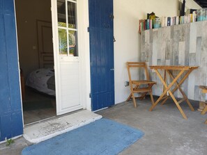 Une pièce avec une porte bleue, une petite table, une chaise et une bibliothèque remplie de livres.