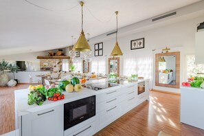 A spacious kitchen with a large island, modern appliances, and pendant lighting. - Corte Benedetto in Montecarlo (Capannori)
