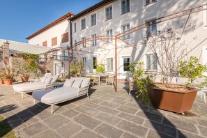 A courtyard with a lounge area, outdoor seating, and potted plants. - Corte Benedetto in Montecarlo (Capannori)