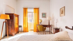A hotel room with a bed, a desk, a chair, a globe, and a lamp. - Rhome Elegant Apartment (Roma)