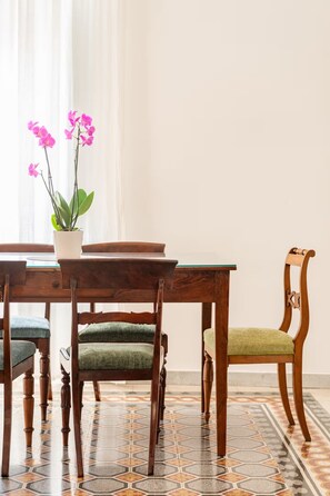 A dining area with a wooden table, chairs, and a potted orchid. - Rhome Elegant Apartment (Roma)