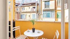 A balcony with a small table and chairs, a potted plant, and a view of neighboring buildings. - Rhome Elegant Apartment (Roma)
