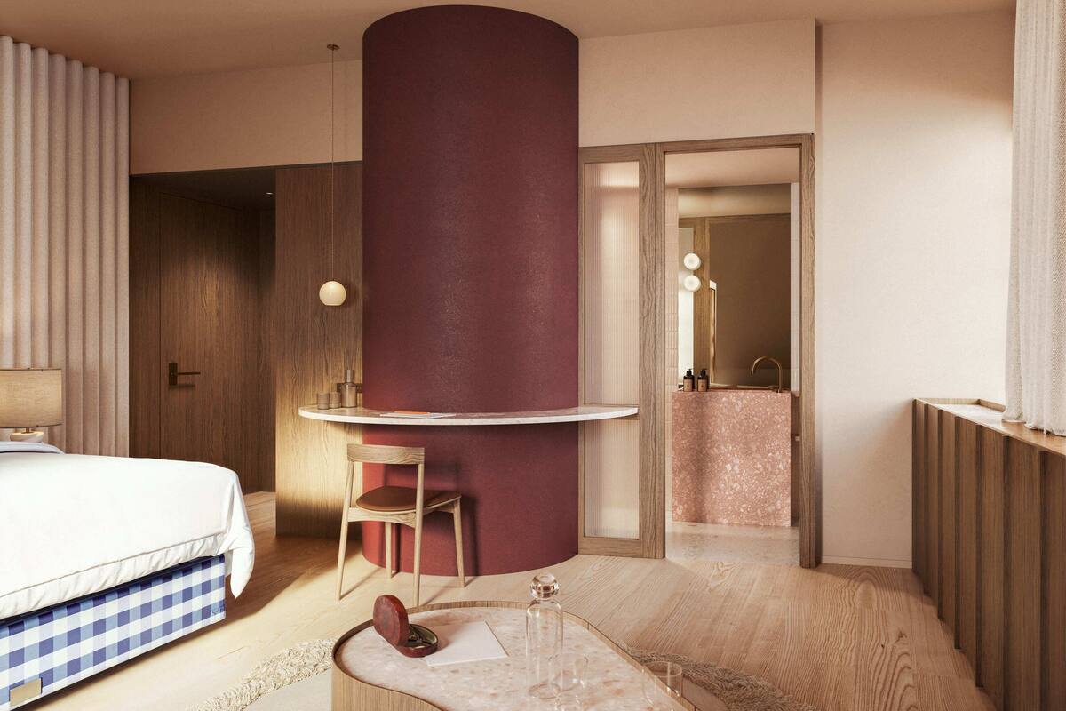 A modern hotel room with a bed, a desk, a chair, and a bathroom visible through an open door.