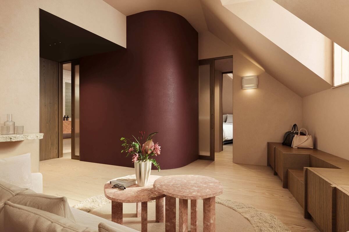A modern interior with a curved wall, a seating area with a vase of flowers, and a wooden bench.