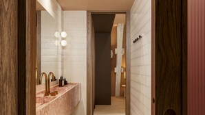 Un baño moderno con lavamanos de mármol, grifos dorados y un espejo con iluminación.