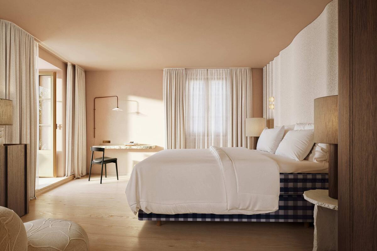A hotel room with a bed, a desk, and a chair.