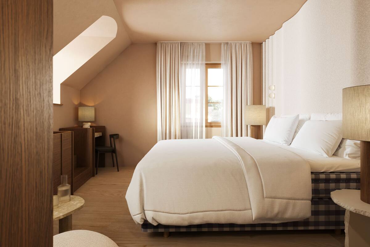 A hotel room with a large bed, a desk, and a chair.