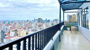 A balcony with a city view, a glass ceiling, and a small seating area. - SKYCONDO Phnom Penh (Phnom Penh)