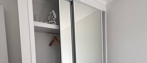 A room with a sliding closet door, a bed, and a small shelf with a hairdryer.