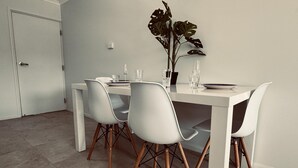 A dining area with a white table, four white chairs, and a potted plant. - Great Location Close to the City and Strand - Great Location Close to the City and Strand (North Ward)