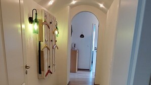 Un corridoio con pavimento in legno, pareti bianche e luci a incasso nel soffitto.