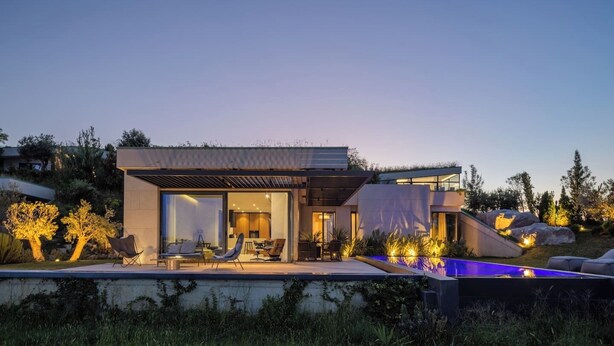 Et moderne hus med pool, udendørs møbler og en overdækket patio.