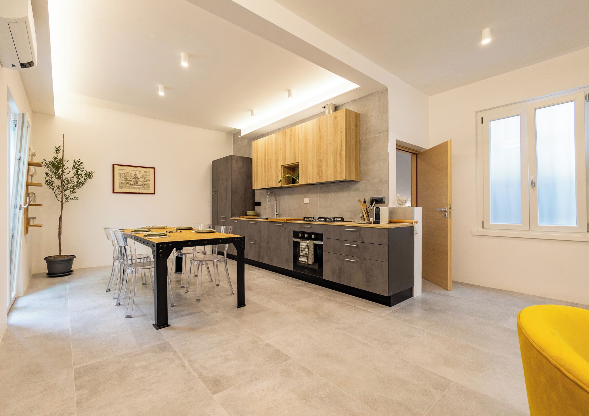 A modern kitchen with a central island, grey cabinets, and a wooden countertop.