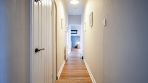 A hallway with wooden flooring and white walls. - Tide & Tee - 2 Bedroom Apartment - Penally - Tenby (Tenby)