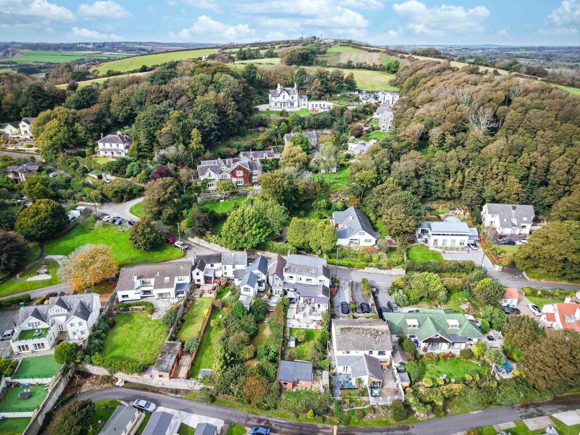 A residential area with houses, roads, and a large estate in the background.