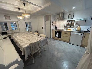 A modern kitchen with a dining area, featuring a large island, built-in oven, and stainless steel appliances.