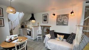 A compact living space with a dining area, kitchenette, and a sofa with patterned cushions.