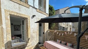 A stone building with a balcony, a wooden bench, and a table with a striped tablecloth.