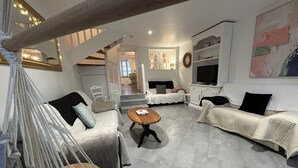 A modern living room with a hammock, two sofas, a coffee table, and a TV.