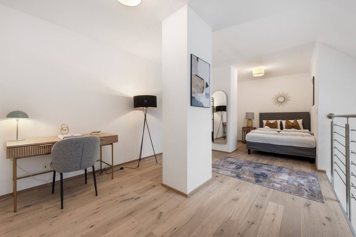 Une chambre à coucher moderne avec un lit, des tables de chevet, un bureau et une chaise.