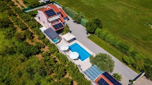 An aerial view of a residential property with a swimming pool, solar panels, and a garden.