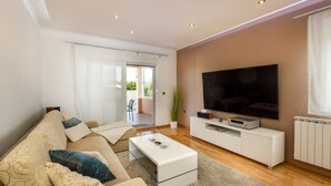 A modern living room with a sofa, coffee table, TV, and a sliding glass door leading to an outdoor area.